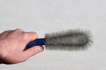Close-up of a hand holding a semicircular brush for removing dust and cobwebs. - obrazy, fototapety, plakaty