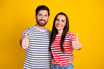 Fototapeta premium Photo portrait of lovely young couple hugging show thumb up wear trendy striped garment isolated on yellow color background