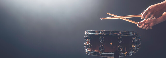 A man plays a snare drum on a dark background, copy space. - obrazy, fototapety, plakaty