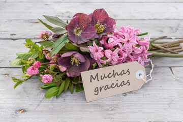 greeting card with Bouquet of pink hyacinths, Christmas roses and card with spanish text: Thank you