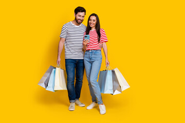 Full length photo of positive couple guy with shopping bags look at smartphone read notification...