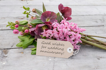Bouquet with pink hyacinths, Christmas roses and card with English text: Good wishes for wedding anniversary