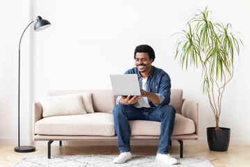 Black Man Sitting On Couch Using Laptop Computer