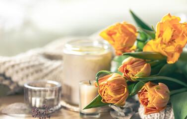 Spring background with yellow tulips, candles and knitted element.
