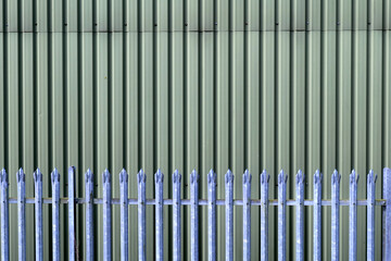 Sharp steel security fence providing protection in front of  a green industrial unit.
