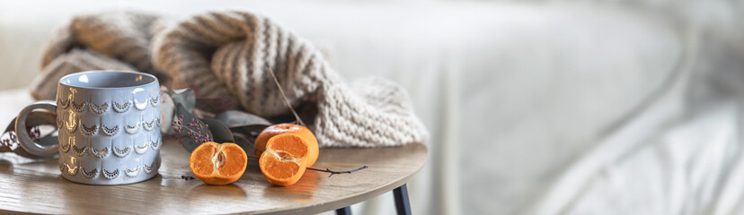 A shiny cup, a knitted element and tangerines on the table in the interior.