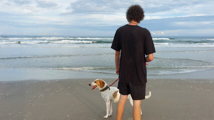 person walking on the beach whit a dog 