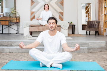 Young couple doing yoga together at home. Family doing sport together concept	