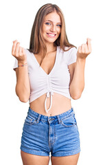 Young beautiful blonde woman wearing casual white tshirt doing money gesture with hands, asking for salary payment, millionaire business