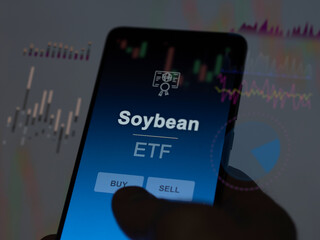 An investor analyzing the soybean etf fund on a screen. A phone shows the prices of Soybean