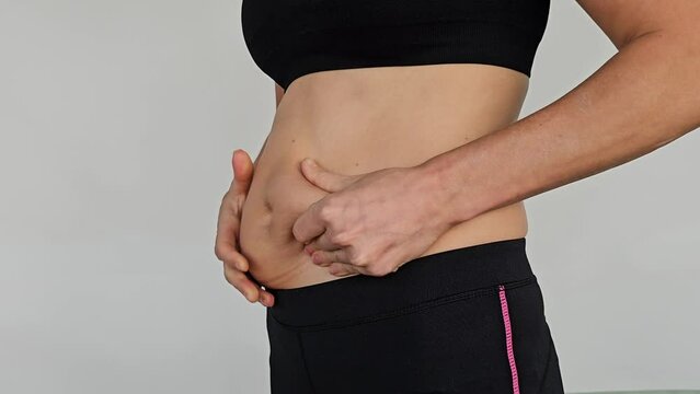 Woman fingers measure belly fat. Obesity, excess weight and pregnancy