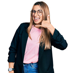 Hispanic young woman wearing business jacket and glasses smiling doing phone gesture with hand and...