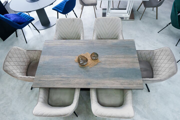 Gray wooden table combined with gray chairs with soft fabric upholstery. There is a black porcelain...