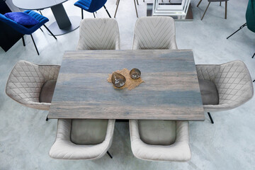 Gray wooden table combined with gray chairs with soft fabric upholstery. There is a black porcelain plate on the table