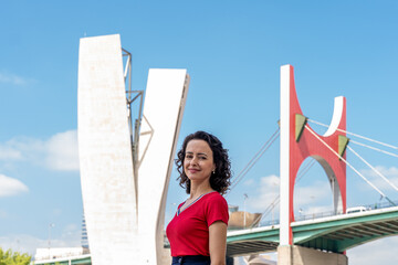 Smiling Woman in Red With the Iconic Bilbao Bridge as a Backdrop