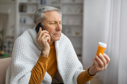 Senior examining medication while on a call - Powered by Adobe
