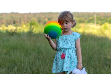 A cute little girl in summer dress holding colored ball	