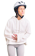 Beautiful brunette young woman wearing bike helmet and sporty clothes with hand on stomach because indigestion, painful illness feeling unwell. ache concept.