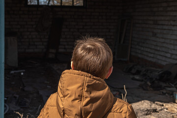 Boy walking next to an abandoned building. Child in danger concept