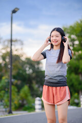 attractive asian woman healthy jogging exercise with headphones  in park outdoor at evening