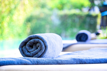 Rolled up blue towels on sunbed around swimming pool in hotel resort