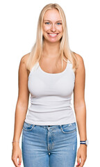 Young blonde girl wearing casual style with sleeveless shirt with a happy and cool smile on face. lucky person.