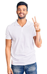Young handsome hispanic man wearing casual clothes smiling looking to the camera showing fingers...