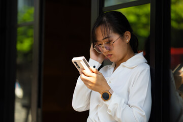 woman using smart phone - Asian woman busy working on mobile phone at moder office workspace. Attractive beautiful Asian business woman working in home office.