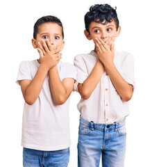 Couple of little brothers together wearing casual clothes shocked covering mouth with hands for mistake. secret concept.