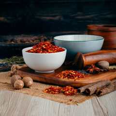 RED CHILLI FLAKES on wooden table background. Herbs, spices and dried food baking ingredient. Mortar and different spices. Cottage kitchen. Product Photography