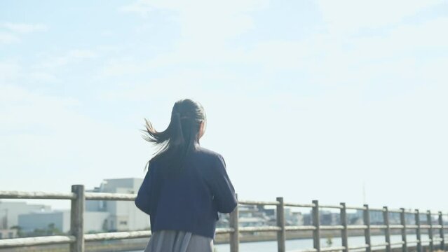 青空の下を走る制服を着た女の子