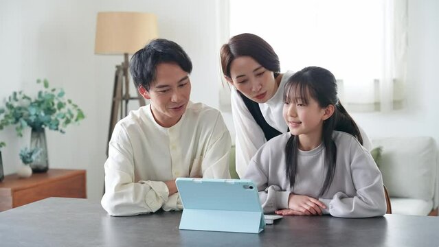 A family of an Asian girl and her parents looking at a tablet PC screen.