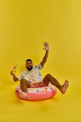 A man with a contemplative expression sits atop a colorful inflatable object, floating effortlessly...