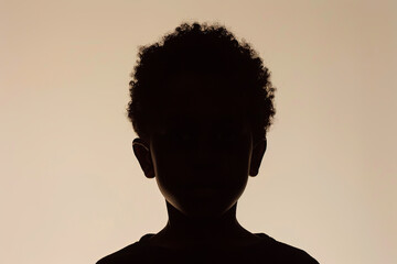 A dark silhouette figure of young boy on brown background, with unclear face feature - obrazy, fototapety, plakaty