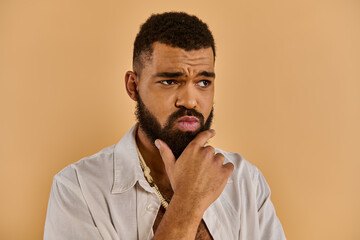 A middle-aged man with a long, bushy beard wearing a crisp white shirt gazes off into the distance with a thoughtful expression.