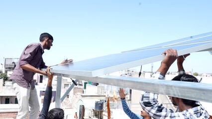Indian workers installing solar panels on roof of house. Maintenance of photovoltaic panel system. Concept of alternative, renewable energy.