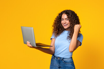 Laptop-holding woman celebrates a victory on yellow
