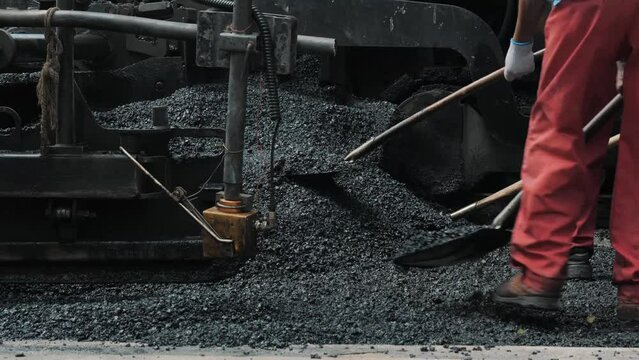 Workers making asphalt with shovels at road construction