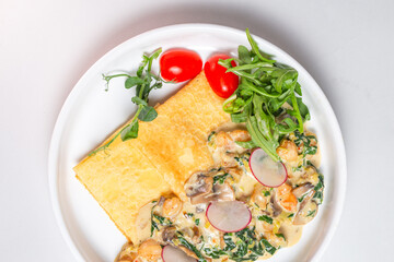 Savory crepe with creamy mushroom sauce and fresh greens on a white plate