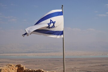 Israeli flag flying on Masada ancient fortress in Israel with Judean Desert horizon