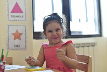 Happy Caucasian girl kid sitting and laughing at a Kindergarten