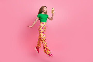 Full length photo of lovely adorable girl blogger wear stylish clothes fly air read sms isolated on pink color background