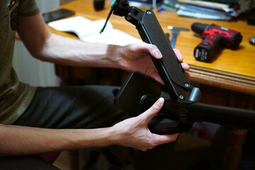 close-up on the hands of a young programmer, an adjustable stand is being assembled to mount a...