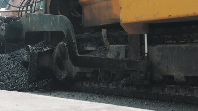 Pavement machine laying fresh asphalt during highway construction
