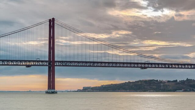 Lisbon city sunrise with April 25 bridge timelapse, River and waterfront early morning. Orange clouds on the sky