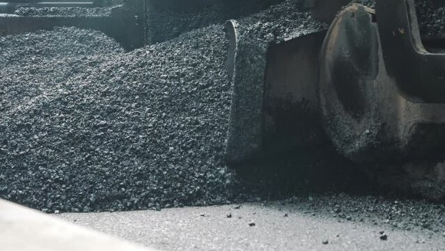 Pavement machine laying fresh asphalt during highway construction