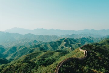 The Great Wall of China snakes through lush green hills its ancient stone structure standing out against a clear azure sky