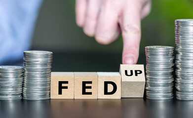 Hand turns wooden cube and changes the expression FED (Federal Reserve System) to 'fed up'.