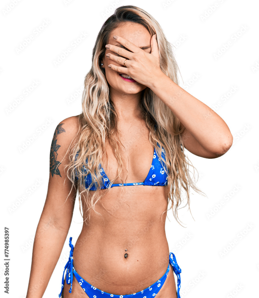 Canvas Prints young blonde woman wearing bikini smiling and laughing with hand on face covering eyes for surprise.