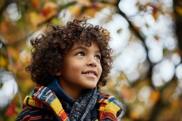 Portrait of a cute little boy with curly hair in autumn park